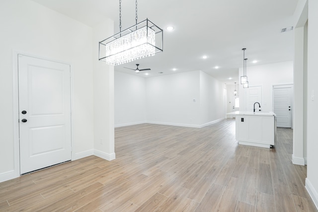 4507 Metropolitan Ave, Dallas, TX 75210 - unfurnished living room with light wood-style floors, baseboards, a chandelier, recessed lighting, and a sink