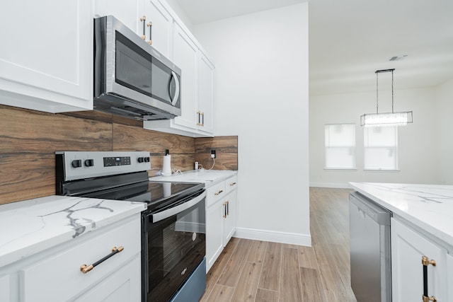 4507 Metropolitan Ave, Dallas, TX 75210 - kitchen with appliances with stainless steel finishes, light wood finished floors, white cabinets, baseboards, and light stone counters