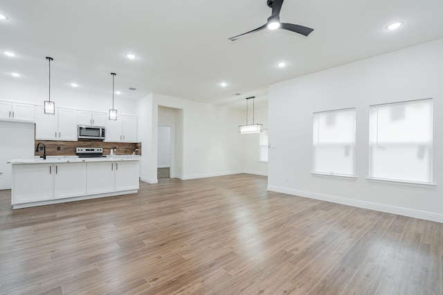 4507 Metropolitan Ave, Dallas, TX 75210 - unfurnished living room featuring ceiling fan, baseboards, light wood finished floors, recessed lighting, and a sink