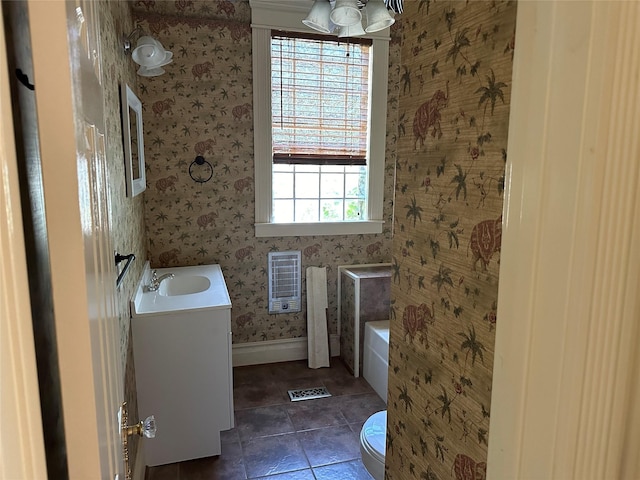 305 Quitman St, Pittsburg, TX 75686 - full bathroom with wallpapered walls, vanity, a tub to relax in, heating unit, and toilet