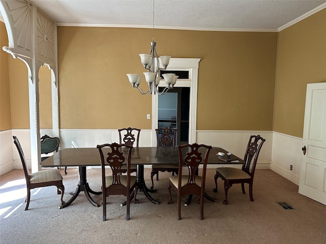 305 Quitman St, Pittsburg, TX 75686 - dining area with a chandelier, carpet flooring, ornamental molding, a wainscoted wall, and a textured ceiling
