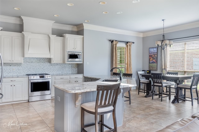187 Waters Edge Dr, Shreveport, LA 71106 - kitchen with appliances with stainless steel finishes, wall chimney range hood, a sink, a chandelier, and backsplash