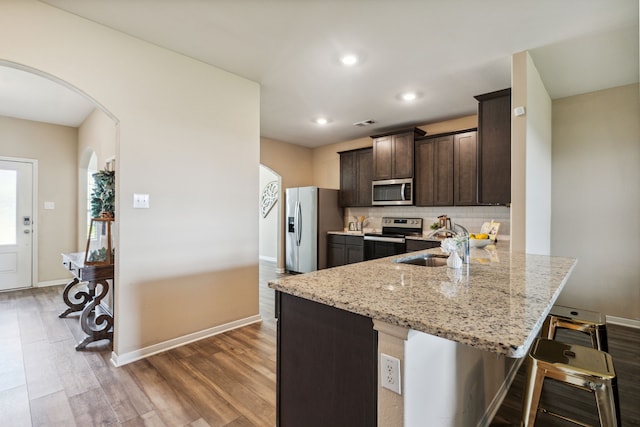 203 Lake Rdg, Princeton, TX 75407 - kitchen featuring stainless steel appliances, arched walkways, a breakfast bar area, dark brown cabinets, and wood finished floors