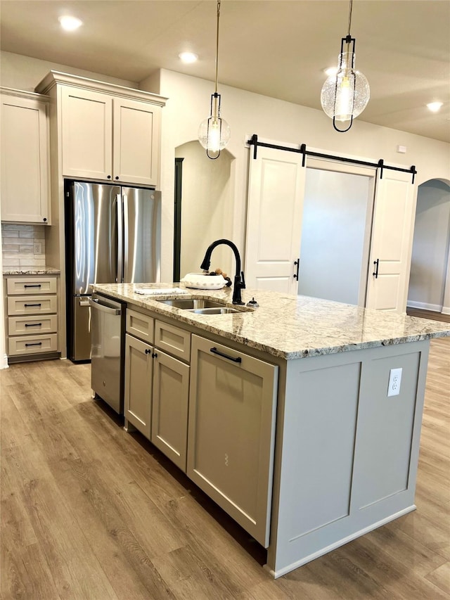 358 Frederick Dr, Robinson, TX 76706 - kitchen featuring stainless steel appliances, a sink, a barn door, a kitchen island with sink, and light wood finished floors