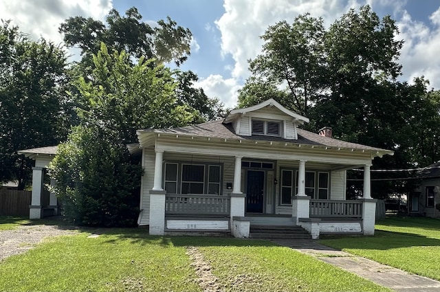 228 N Texas St, Pittsburg, TX 75686 - bungalow featuring a front lawn, covered porch, a chimney, and roof with shingles