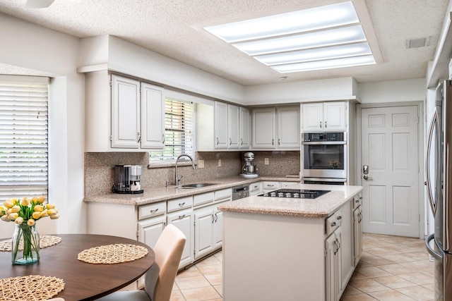 6737 Lake Shore Dr, Garland, TX 75044 - kitchen featuring appliances with stainless steel finishes, light tile patterned floors, tasteful backsplash, a kitchen island, and a textured ceiling