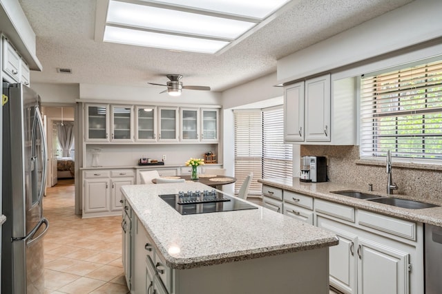 6737 Lake Shore Dr, Garland, TX 75044 - kitchen featuring freestanding refrigerator, a kitchen island, a textured ceiling, glass insert cabinets, and a ceiling fan