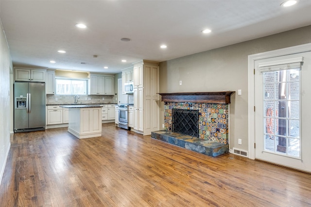 3635 Merrell Rd, Dallas, TX 75229 - kitchen with stainless steel appliances, recessed lighting, dark wood-style flooring, a fireplace, and tasteful backsplash