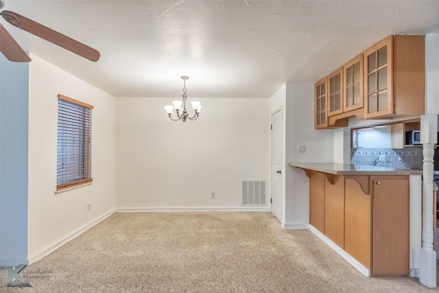 25 Spears Cir, Abilene, TX 79601 - kitchen featuring a chandelier, brown cabinetry, glass insert cabinets, light colored carpet, and baseboards