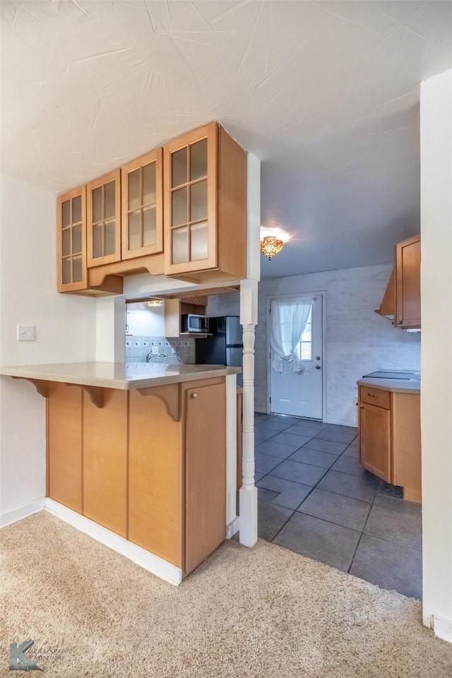 25 Spears Cir, Abilene, TX 79601 - kitchen featuring glass insert cabinets, a breakfast bar area, stainless steel microwave, carpet flooring, and baseboards