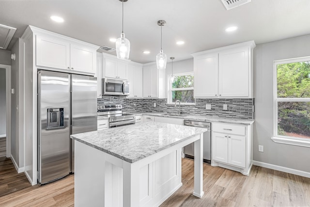 915 Comanche Cove Dr, Granbury, TX 76048 - kitchen featuring appliances with stainless steel finishes, a sink, decorative backsplash, white cabinetry, and light wood-type flooring