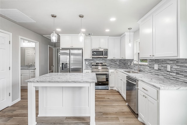 915 Comanche Cove Dr, Granbury, TX 76048 - kitchen featuring stainless steel appliances, a sink, light wood finished floors, backsplash, and white cabinetry