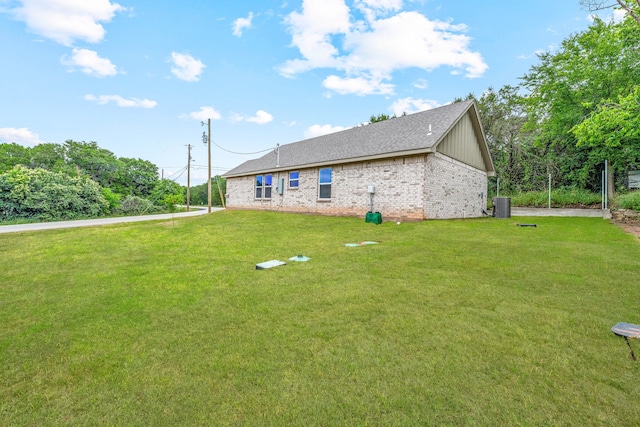 915 Comanche Cove Dr, Granbury, TX 76048 - view of home's exterior with central air condition unit, a lawn, brick siding, and roof with shingles