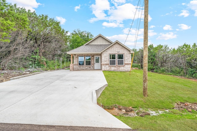 915 Comanche Cove Dr, Granbury, TX 76048 - view of front of house with brick siding, driveway, a front yard, and board and batten siding
