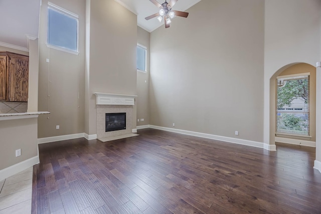 7605 Chief Spotted Tail Dr, Mckinney, TX 75070 - unfurnished living room featuring a ceiling fan, dark wood-type flooring, a high ceiling, a fireplace, and baseboards
