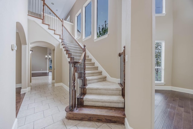 7605 Chief Spotted Tail Dr, Mckinney, TX 75070 - staircase featuring a towering ceiling, arched walkways, baseboards, and tile patterned floors