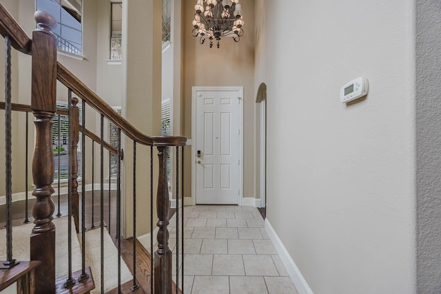 7605 Chief Spotted Tail Dr, Mckinney, TX 75070 - entrance foyer with arched walkways, a towering ceiling, stairs, a chandelier, and light tile patterned floors