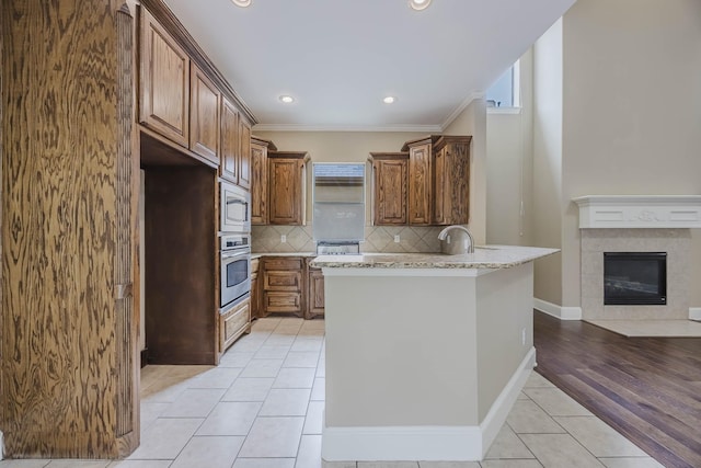 7605 Chief Spotted Tail Dr, Mckinney, TX 75070 - kitchen featuring stainless steel appliances, light tile patterned floors, a peninsula, decorative backsplash, and light stone counters