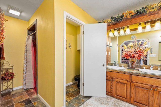 2514 Good Shepherd Dr, Brownwood, TX 76801 - bathroom featuring stone tile floors, double vanity, baseboards, and curtained shower