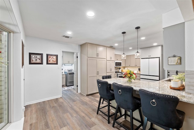 2514 Good Shepherd Dr, Brownwood, TX 76801 - kitchen featuring white appliances, a peninsula, a breakfast bar area, light stone counters, and recessed lighting