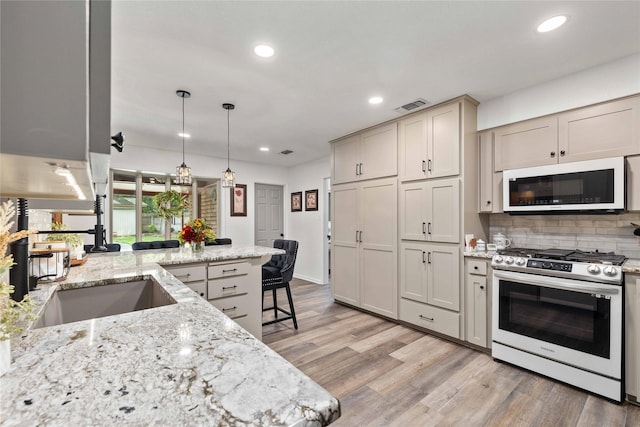 2514 Good Shepherd Dr, Brownwood, TX 76801 - kitchen with stainless steel range with gas stovetop, white microwave, light wood-type flooring, tasteful backsplash, and recessed lighting