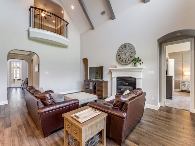 3051 Kennington Dr, Prosper, TX 75078 - living room with arched walkways, high vaulted ceiling, dark wood finished floors, a glass covered fireplace, and baseboards