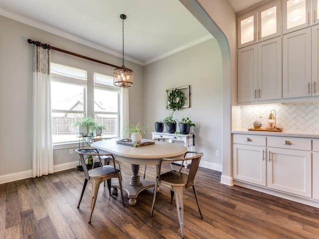 3051 Kennington Dr, Prosper, TX 75078 - dining area with baseboards, dark wood-style floors, ornamental molding, a chandelier, and arched walkways