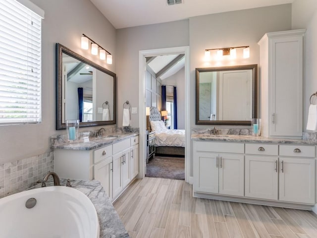 3051 Kennington Dr, Prosper, TX 75078 - full bath featuring two vanities, a tub to relax in, connected bathroom, and wood finished floors
