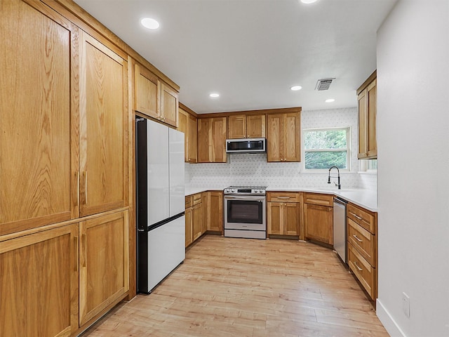 351 Oak Creek Dr, New Hope, TX 75071 - kitchen with stainless steel appliances, light wood-style floors, brown cabinetry, light countertops, and backsplash
