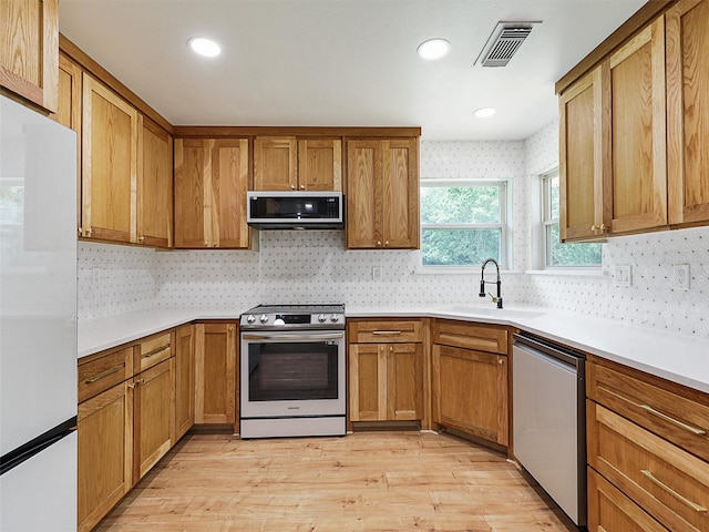 351 Oak Creek Dr, New Hope, TX 75071 - kitchen with stainless steel appliances, a sink, tasteful backsplash, brown cabinets, and light wood-style flooring
