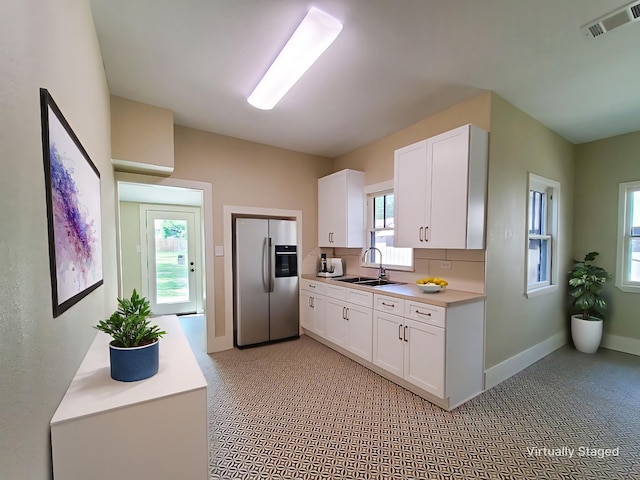 2107 Homan Ave, Waco, TX 76707 - kitchen featuring stainless steel refrigerator with ice dispenser, white cabinets, light countertops, decorative backsplash, and light colored carpet