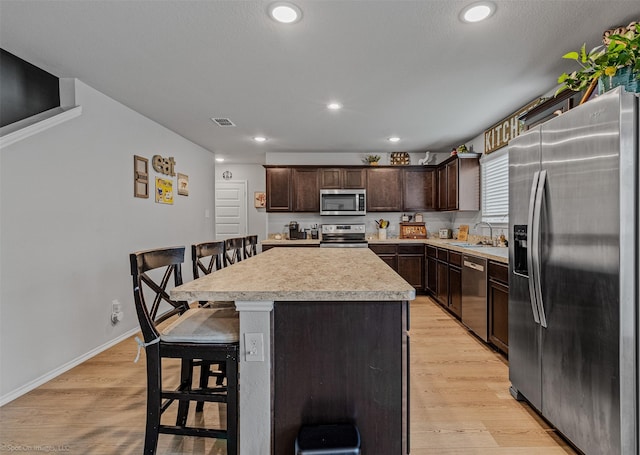 129 Clear Creek Ln, Terrell, TX 75160 - kitchen with appliances with stainless steel finishes, a sink, dark brown cabinets, light countertops, and a kitchen island