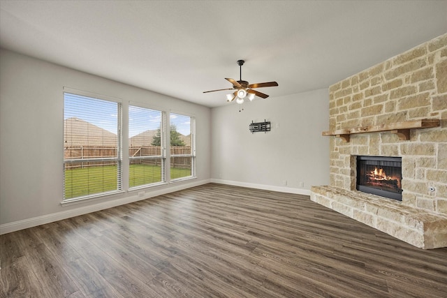 946 Mangrove Dr, Fate, TX 75087 - unfurnished living room featuring a stone fireplace, baseboards, ceiling fan, and wood finished floors