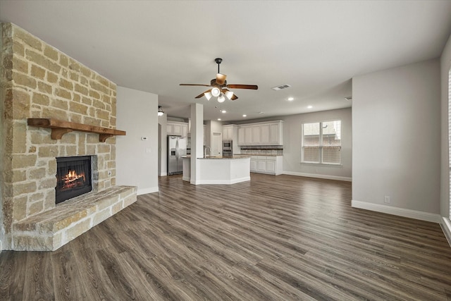946 Mangrove Dr, Fate, TX 75087 - unfurnished living room with a stone fireplace, ceiling fan, a sink, baseboards, and recessed lighting