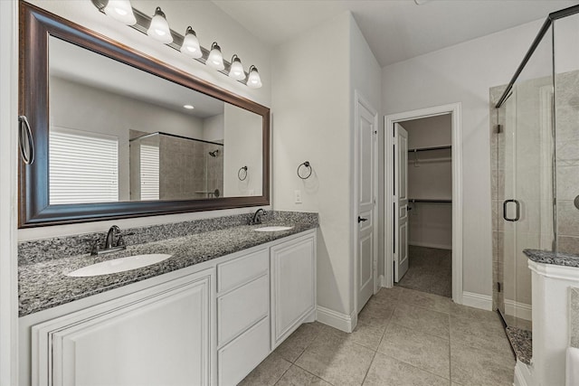 946 Mangrove Dr, Fate, TX 75087 - full bath with a stall shower, double vanity, a walk in closet, tile patterned flooring, and baseboards