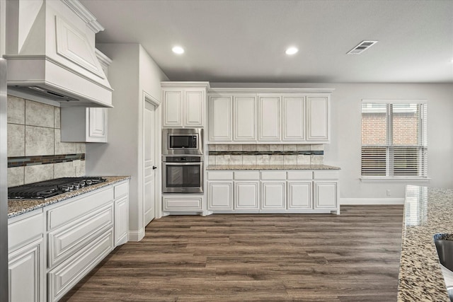 946 Mangrove Dr, Fate, TX 75087 - kitchen featuring stainless steel appliances, custom range hood, dark wood finished floors, baseboards, and tasteful backsplash