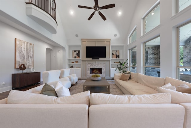 3690 Guinn Gate Dr, Frisco, TX 75034 - living area with high vaulted ceiling, a ceiling fan, a lit fireplace, baseboards, and built in shelves