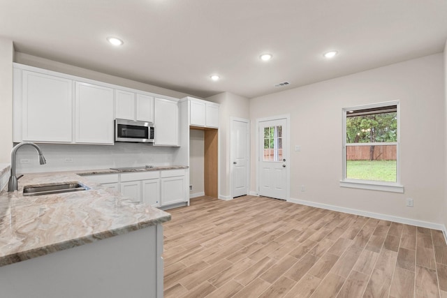 301 Kalura Way, Tool, TX 75143 - kitchen with stainless steel microwave, a sink, light stone counters, white cabinets, and light wood-style flooring