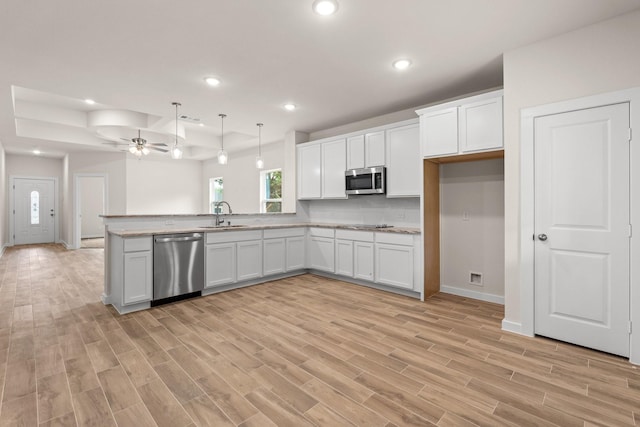 301 Kalura Way, Tool, TX 75143 - kitchen with stainless steel appliances, a sink, a ceiling fan, white cabinets, and light wood-style flooring