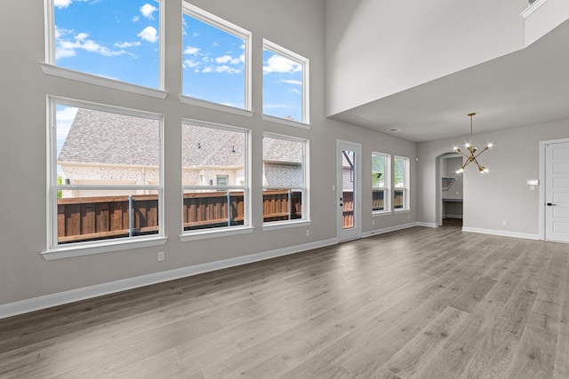 2013 Tolleson Dr, Fort Worth, TX 76008 - unfurnished living room with a chandelier, wood finished floors, baseboards, and a high ceiling