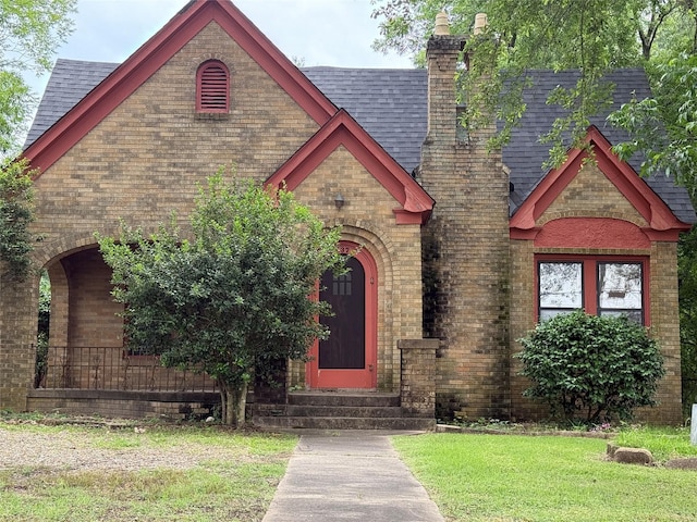 437 Jefferson St, Pittsburg, TX 75686 - english style home featuring entry steps, a shingled roof, a chimney, brick siding, and a front lawn