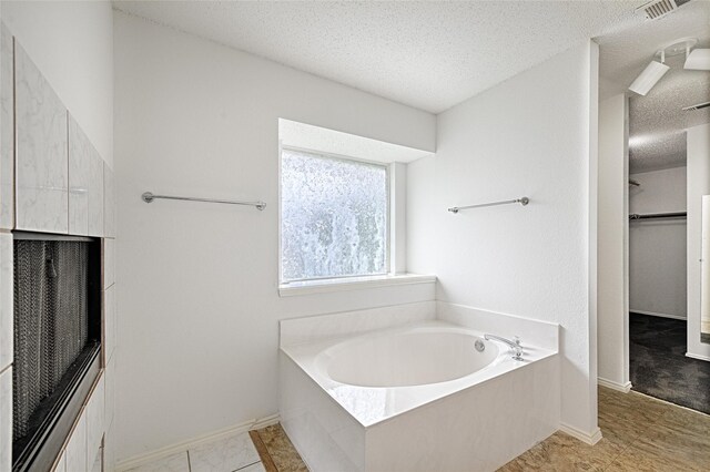 6018 San Marino Ct, Rowlett, TX 75089 - bathroom with a textured ceiling, a garden tub, a walk in closet, and baseboards