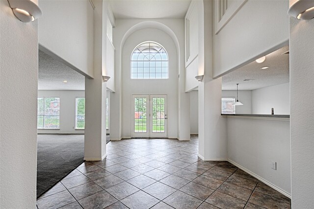 6018 San Marino Ct, Rowlett, TX 75089 - carpeted foyer entrance featuring baseboards, a towering ceiling, tile patterned floors, and a textured ceiling