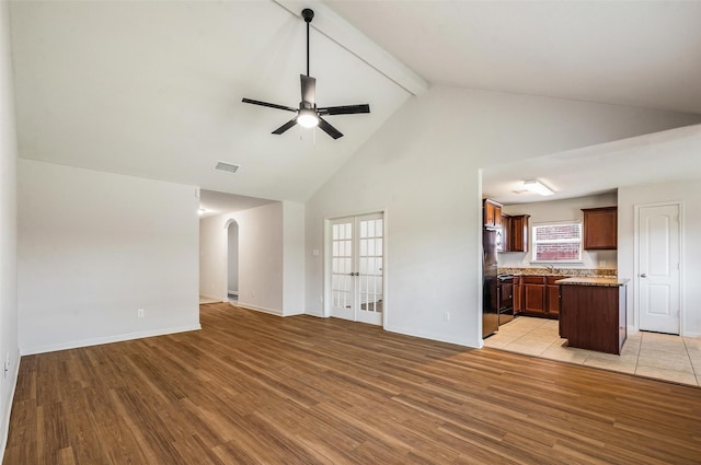 1206 Lombardy Dr, Princeton, TX 75407 - unfurnished living room featuring a ceiling fan, high vaulted ceiling, light wood finished floors, beam ceiling, and french doors