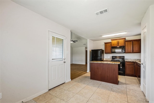 1206 Lombardy Dr, Princeton, TX 75407 - kitchen featuring black appliances, a kitchen island, light tile patterned flooring, baseboards, and light stone countertops