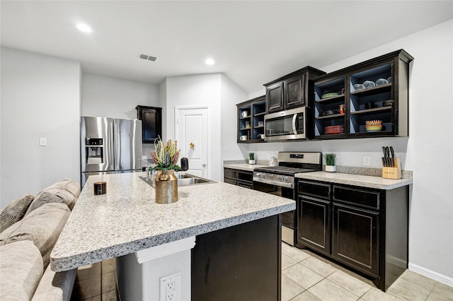 16561 Portage St, Justin, TX 76247 - kitchen featuring appliances with stainless steel finishes, light countertops, light tile patterned flooring, recessed lighting, and a kitchen bar