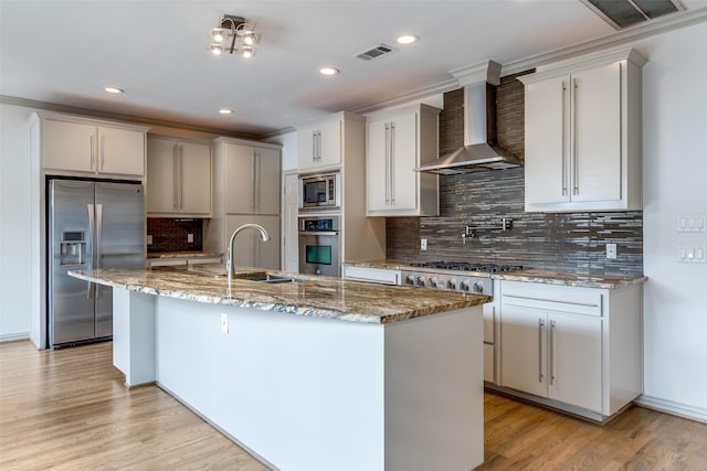3719 Douglas Ave, Dallas, TX 75219 - kitchen featuring appliances with stainless steel finishes, wall chimney exhaust hood, a kitchen island with sink, backsplash, and recessed lighting
