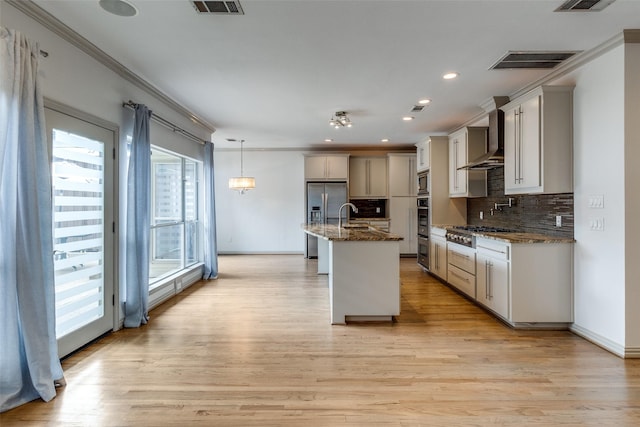 3719 Douglas Ave, Dallas, TX 75219 - kitchen with appliances with stainless steel finishes, ornamental molding, tasteful backsplash, an island with sink, and light wood-style flooring