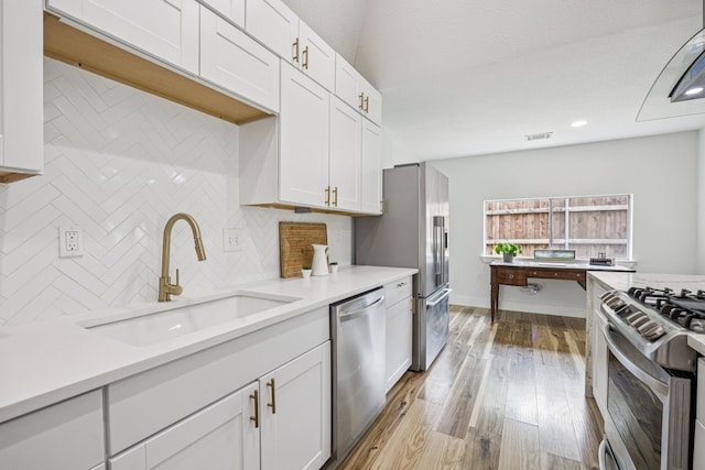 6607 Leameadow Dr, Dallas, TX 75248 - kitchen featuring appliances with stainless steel finishes, a sink, tasteful backsplash, white cabinetry, and light countertops
