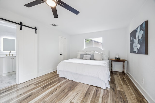 6607 Leameadow Dr, Dallas, TX 75248 - bedroom with a sink, a barn door, ceiling fan, light wood finished floors, and connected bathroom